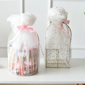 Detail of golden metal gift basket with white organza pouch and pink ribbon bow detail