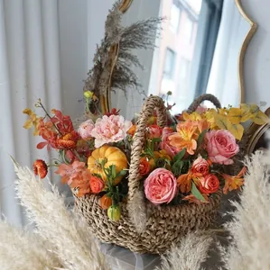 Cesto di fiori intrecciato a mano con rose rosa e mini zucca in una calda scena rustica