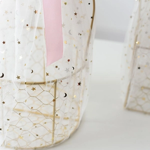 Detail of white mesh fabric with golden stars and moons for gift basket decoration