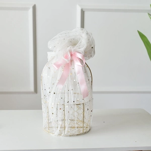 Detail of golden metal gift basket with star print mesh wrap and pink satin ribbon bow