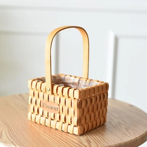 Close-up of woven wood flower basket with arched handle and Flower label detail