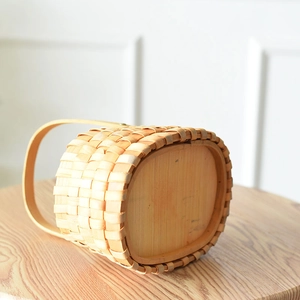 Close-up of hand-woven wood basket with solid base and handle in Nordic style