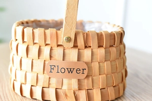 Close-up of handwoven wooden flower basket with leather label and gold rivet details