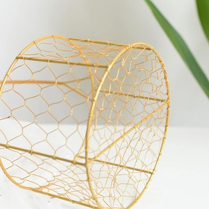Close-up of gold iron gift basket showing hexagonal wire mesh and polished metallic finish