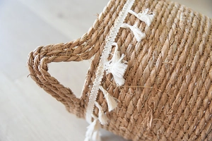 Close-up of bohemian rattan flower basket featuring handcrafted weave and white fringe tassel