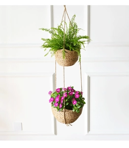 Detail of hanging double-tier natural seagrass planter basket with green ferns and flowers