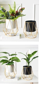 Detail view of black and white metal plant pots with gold geometric stands for tabletops