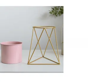 Detail view of a pink cylindrical metal planter on a modern gold geometric metal stand