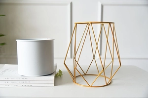 Detail of modern gold geometric metal stand with minimalist white cylinder plant pot