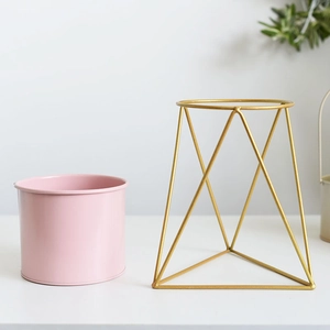 Modern Nordic pink metal flower pot with geometric gold iron stand on white background