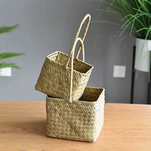 Detail of two handmade seagrass woven baskets with handles on a rustic wooden table