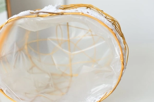 Macro detail of golden metal wire flower basket with white lace trim and plastic liner