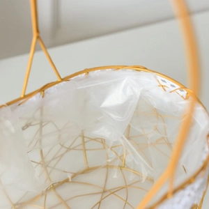 Golden wire mesh flower basket with white lace trim and waterproof lining for picnic storage