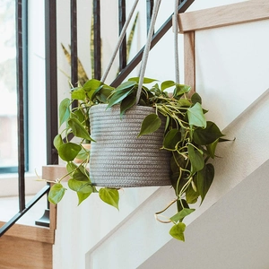 Gray cotton linen hanging planter basket for indoor plants on a wooden staircase