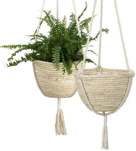 Detail of two handmade woven hanging planters with tassels and lush green ferns