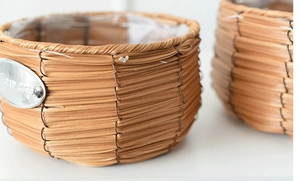 Close-up of woven rattan planter with waterproof plastic lining and Flowers metal label