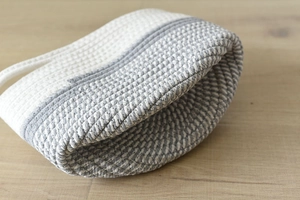 Detail of grey and white cotton rope woven storage basket with durable handles