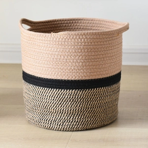 Detail of a 25x25cm woven cotton rope storage basket with dual handles on wood floor