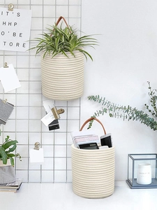 Macro view of woven cotton hanging plant basket with brown leather strap and mesh background