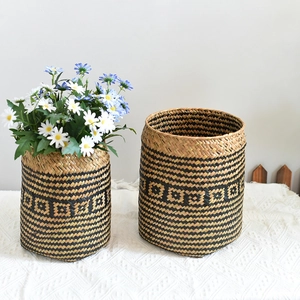 Close-up of hand-woven seagrass basket featuring black diamond pattern and dry flowers
