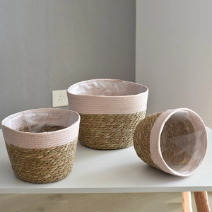 Three sizes of woven seagrass plant baskets with pink accents and waterproof liners