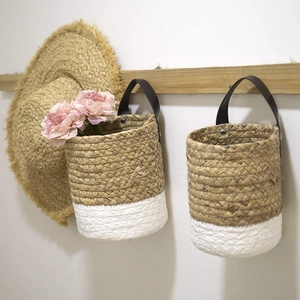 Detail of bohemian seagrass woven wall hanging baskets with sturdy brown leather straps