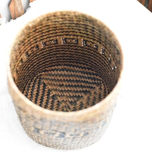 Detail of hand-woven cylindrical bamboo basket with dark geometric folk patterns