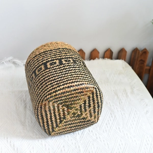 Detail of hand-woven cylindrical storage basket featuring black checkerboard grass patterns
