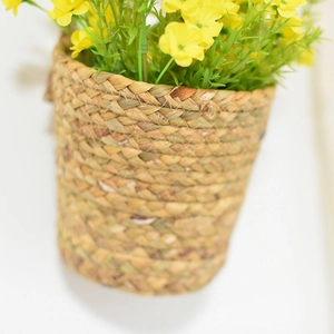 Detail of a wall-mounted seagrass basket with yellow flowers and natural woven textures