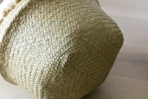 Detailed macro view of handcrafted woven seagrass basket texture with soft white fringe trim