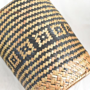 Detail of hand-woven storage basket featuring black and natural geometric fiber texture