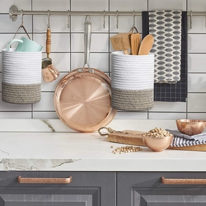 Set of two woven cotton rope hanging baskets with leather handles in a modern kitchen