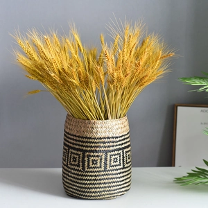 Handwoven natural fiber storage basket with black geometric patterns and dried wheat ears