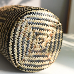 Close-up of hand-woven bamboo basket with black and natural twill cross pattern