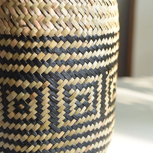 Detail of hand-woven basket showing the natural fiber weave and black geometric pattern