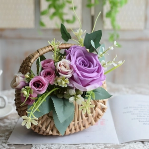 Handwoven wicker flower basket with purple and pink faux roses on a white lace tablecloth