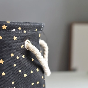 Close-up of canvas storage bag showing golden star patterns and sturdy cotton rope handle