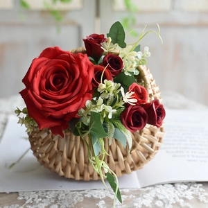 Detailed view of woven rattan basket with artificial red roses and lush green leaves