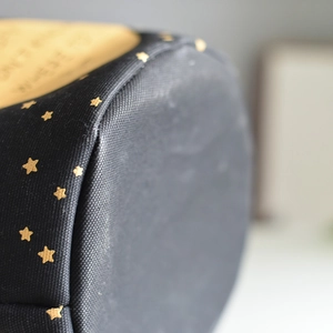 Macro detail of black linen storage bag showing gold star print and stitching quality