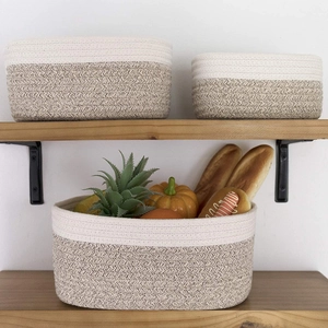 Set of three cotton rope storage baskets with fruit and bread on wooden shelf