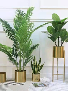 Golden cylindrical metal flower pots with faux indoor plants and minimalist tripod stand