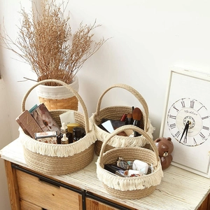 Detail of woven jute storage baskets with white cotton tassels and circular handles