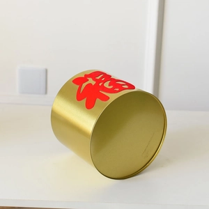 Detail view of gold metal cylinder storage canister featuring a red Fu character design