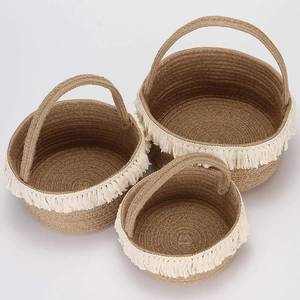 Detail of three nested woven baskets with white fringe trim and round handles
