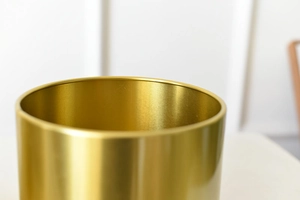 Close-up of golden brushed metal texture on a modern cylindrical flower vase