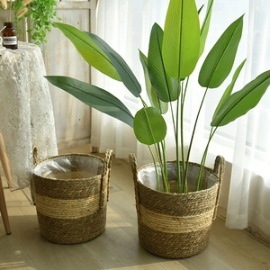 Handwoven straw planters with dual handles and waterproof liners in home setting