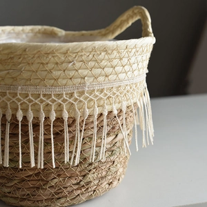 Detailed view of handmade straw plant basket with elegant white fringe tassel accents