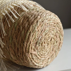 Macro shot of circular seagrass basket with bohemian fringe detail and spiral weave