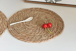 Close-up of a round woven seagrass placemat with cherries and a white spoon