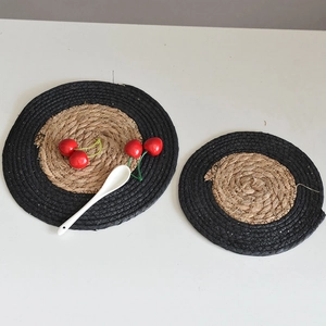 Detail of round woven seagrass coasters with contrast black edge in a set of two